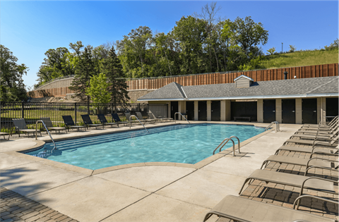 Apartments set in a nature preserve with a huge swimming pool with poolside lounge chairs and scenic views at Claremont Apartments in Minnetonka Minnesota