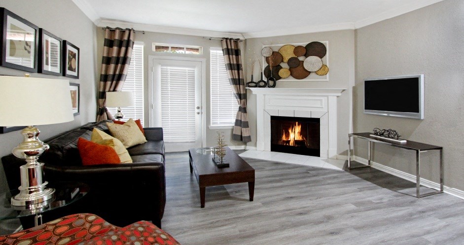 Luxury apartments with spacious living room, wood burning fireplace,  French door, lots of natural light, and gray colored walls at Lenox Village Apartments in Lincoln, NE.