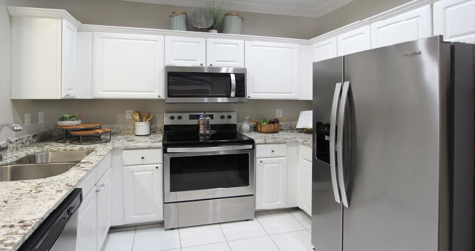 Luxury apartments with granite countertops, white cabinets, stainless steel appliances, and side-by-side refrigerator at TurtleCreek apartments in West Des Moines, Iowa