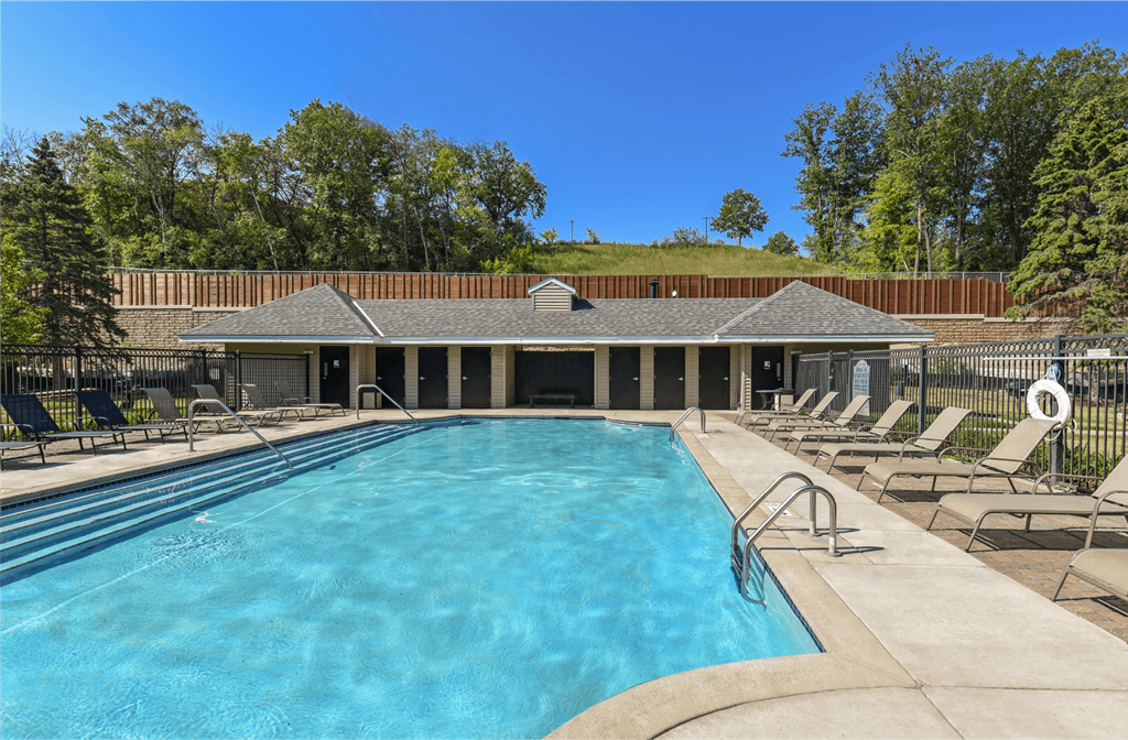 Apartments set in a nature preserve with a huge swimming pool with poolside lounge chairs and scenic views at Claremont Apartments in Minnetonka Minnesota
