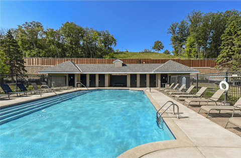 Apartments set in a nature preserve with a huge swimming pool with poolside lounge chairs and scenic views at Claremont Apartments in Minnetonka Minnesota