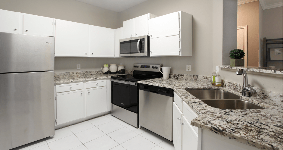 Spacious kitchen with white cabinets, granite countertops, stainless steel appliances, and porcelain tile floors at Breckenridge Apartments in southwest Omaha, Nebraska