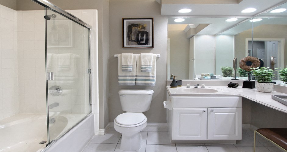 Luxury bathroom with tiled floors, oval soaking tub, built-in vanity, cultured marble vanity, glass shower and white cabinets in at TurtleCreek apartments in West Des Moines, Iowa