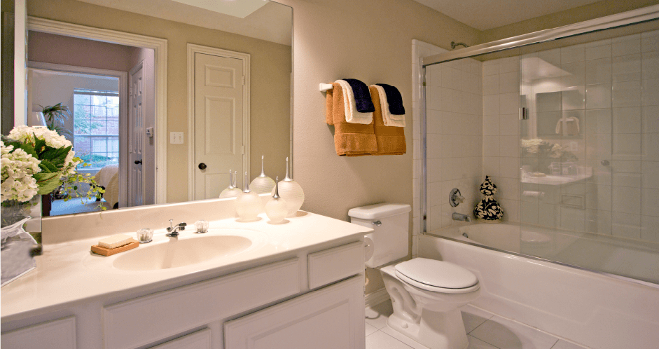Luxury bathroom with white cabinets, cultured marble vanity, oval soaking tub, and glass shower at The Saxony Apartments