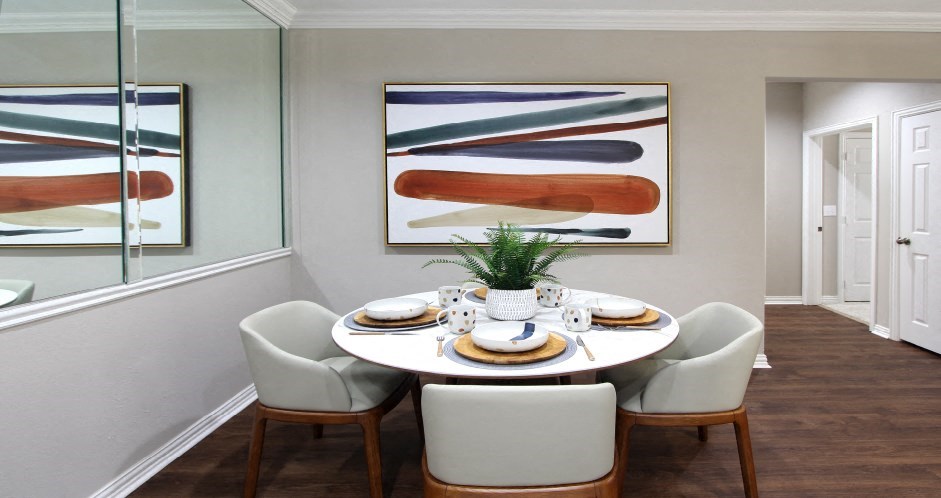 Spacious dining room with plank wood floors and mirror accent wall at Prestonbridge Apartments in North Dallas