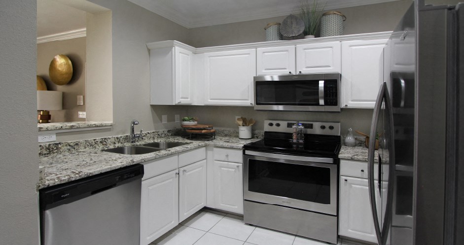 Luxury apartments with granite countertops, white cabinets, stainless steel appliances, and side-by-side refrigerator at TurtleCreek apartments in West Des Moines, Iowa