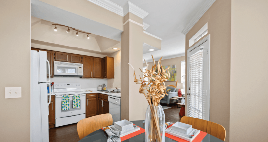 Spacious kitchen with custom home cabinets, side-by-side refrigerator, spacious dining room, and crown molding at Tuscany Park Apartments in Houston.
