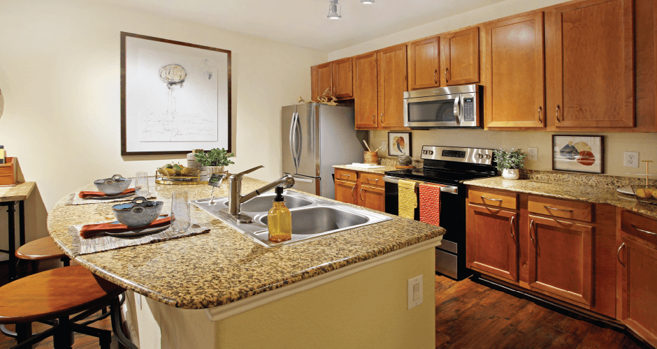 Luxury apartments with hardwood floors, granite countertops, side-by-side refrigerator, and stainless appliances at The Voss Apartments in Houston.