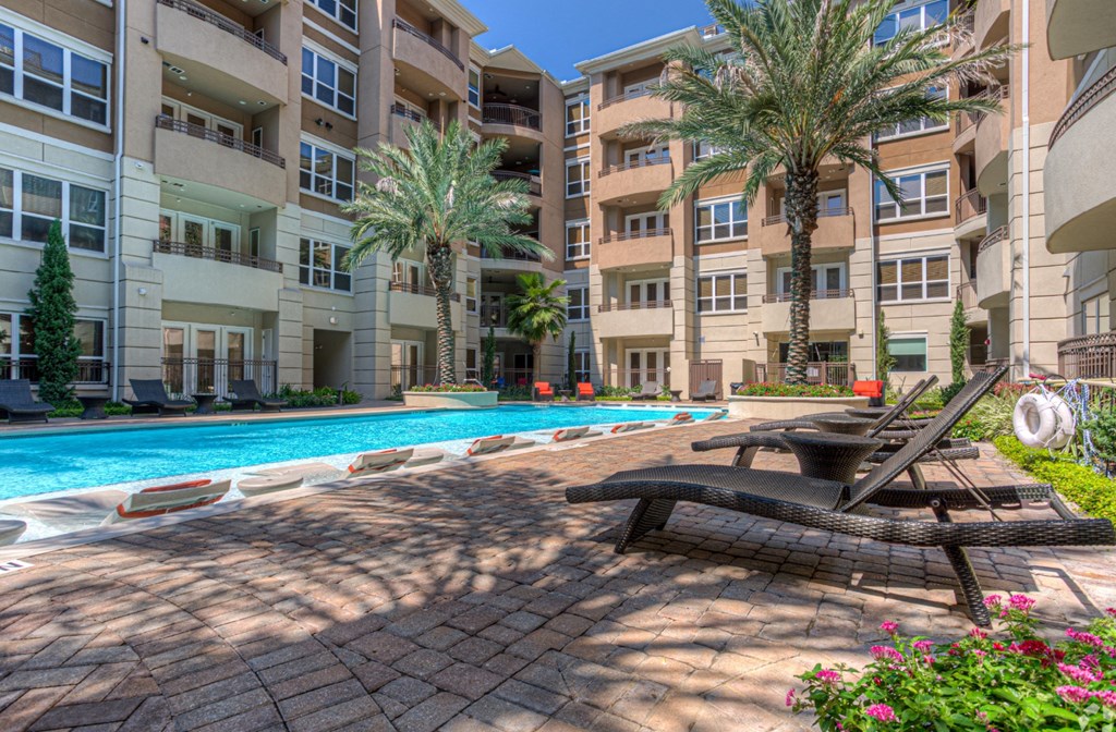 Luxury apartments with resort-style pool and palm trees, fountains, lap lane, and pool-side lounge chairs at Tuscany Walk Apartments in Houston