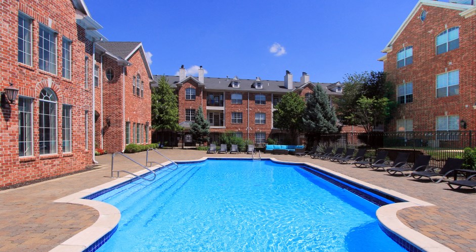 Luxury apartments with red brick exterior, huge swimming pool, poolside lounge chairs, and lush landscaping at TurtleCreek apartments in West Des Moines, Iowa