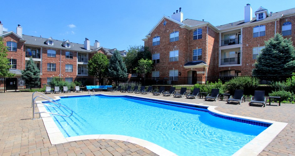 Luxury apartments with red brick exterior, huge swimming pool, poolside lounge chairs, grilling station, and lush landscaping at TurtleCreek apartments in West Des Moines, Iowa