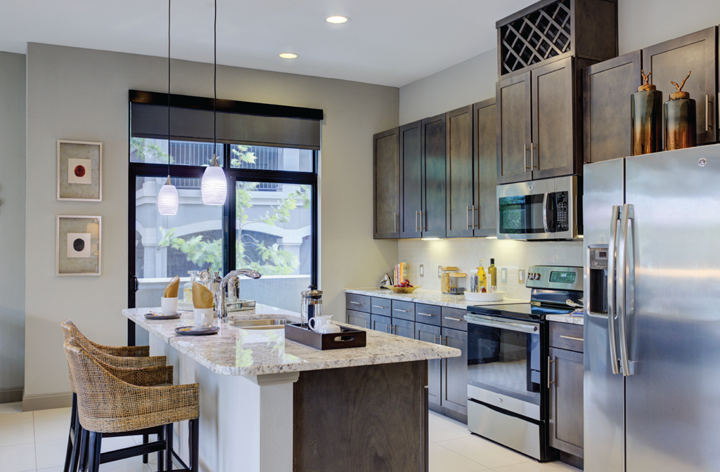 Luxury apartments with spacious kitchens with granite countertops, large granite slab island, built-in wine rack, and stainless appliances at Le Palais Apartments in Houston.