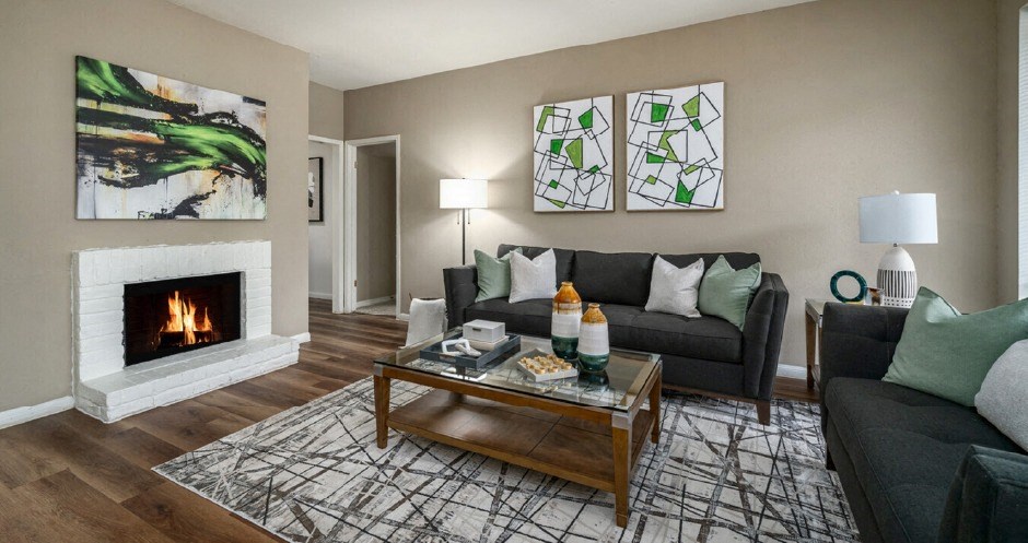 Spacious living room with wood burning fireplace and grey painted walls at Woodlake on the Bayou Apartments in Houston.