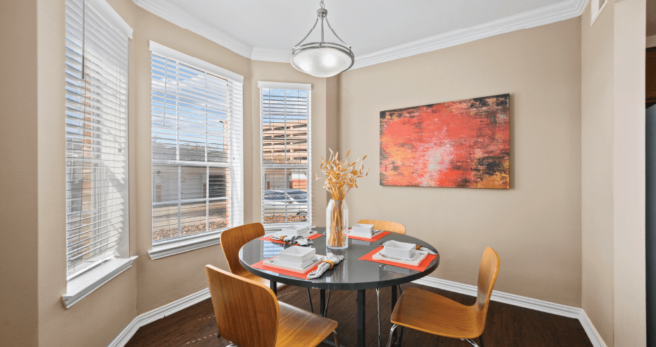 Spacious dining room with large bay windows and hardwood floors at Tuscany Park Apartments in Houston.