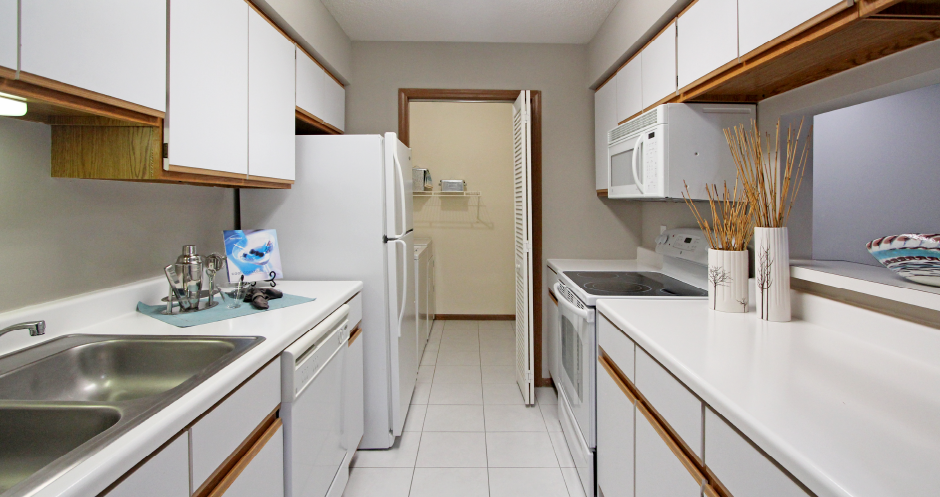 Kitchen with lots of cabinet space, lots of counter space, gray wall color, and full-size washer and dryer at The Vanderbilt Apartments in Omaha, Nebraska