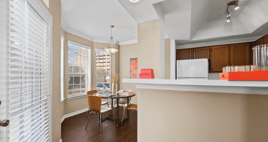 Spacious dining room with large bay windows and wood plank floors at Tuscany Park Apartments in Houston.