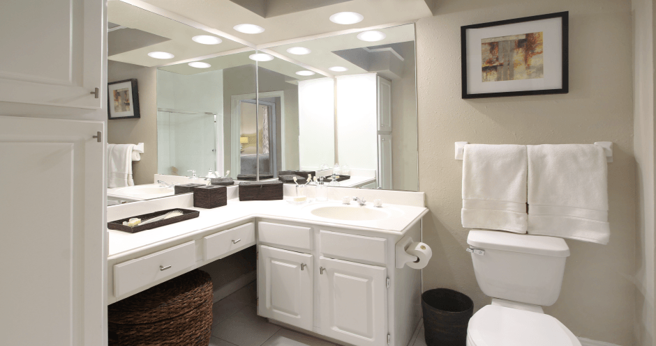Luxury apartments with white cabinets, linen closet, extra cabinet space, cultured marble vanity, built-in vanity, and porcelain tiled floor at The Biltmore Apartments in Omaha, Nebraska