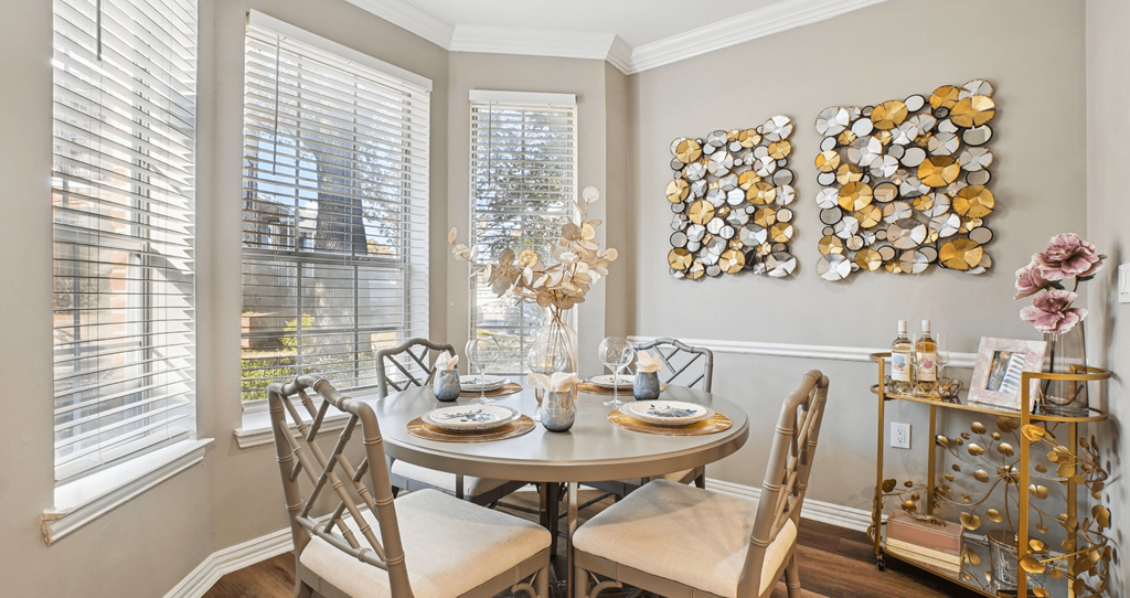 A dining room with a table set for two and a chandelier.