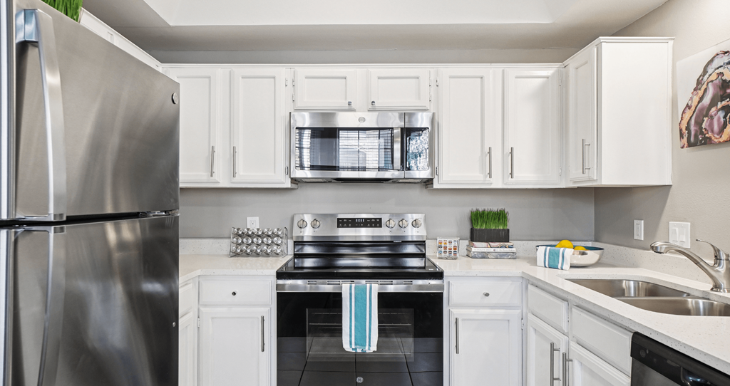 A modern kitchen with white cabinets and stainless steel appliances.