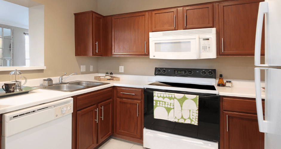 Spacious u-shaped kitchen with lots of cabinet space, lots of counter space, porcelain tile floor, and rich brown toned cabinets at The Biltmore Apartments in Omaha, Nebraska