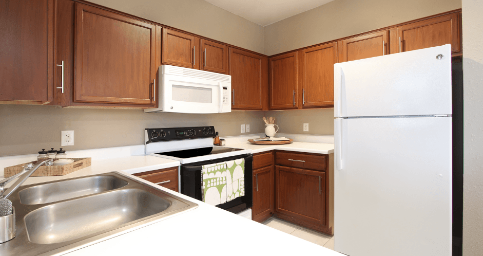 Spacious u-shaped kitchen with lots of cabinet space, lots of counter space, porcelain tile floor, and rich brown toned cabinets at The Biltmore Apartments in Omaha, Nebraska