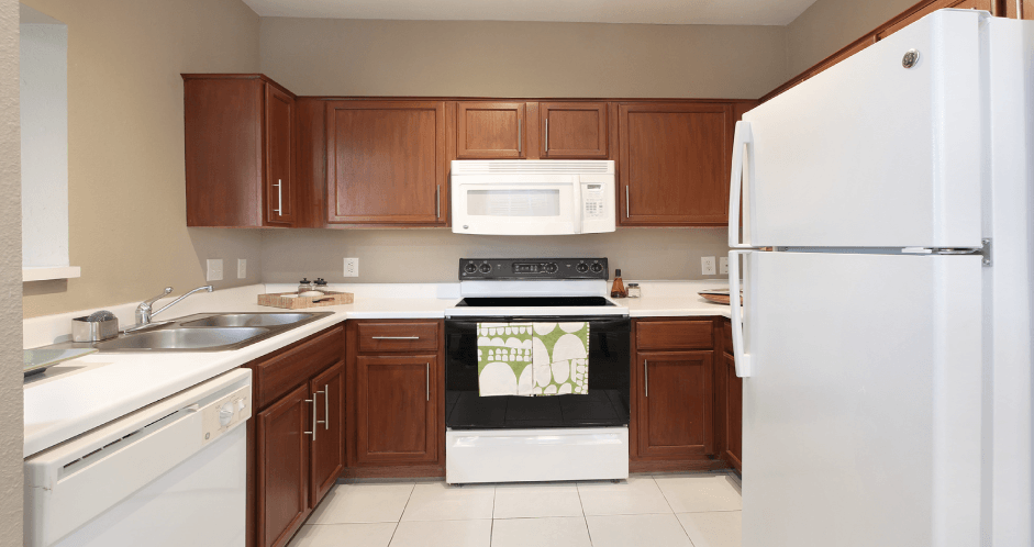Spacious u-shaped kitchen with lots of cabinet space, lots of counter space, porcelain tile floor, and rich brown toned cabinets at The Biltmore Apartments in Omaha, Nebraska
