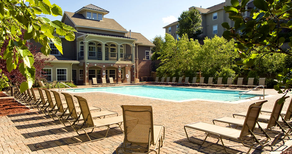 Resort-style pool with large sundeck, poolside lounge chairs, lush landscaping, beautiful landscaping, park-like setting with lots of trees at Breckenridge Apartments in southwest Omaha, Nebraska