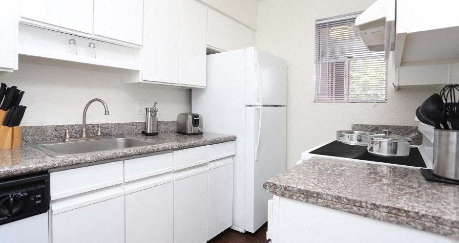 Kitchen with white cabinets, lots of counter space, lots of cabinet space, granite counter tops, and wood plank floors at Briarwood apartments in Houston, Texas