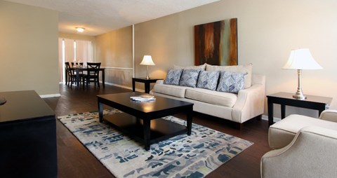 A living room with a white couch, a coffee table, and a painting on the wall.