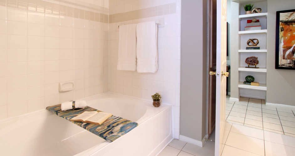 Luxury apartments with spacious bathrooms with tiled floors and showers, oval soaking tub, granite countertop, washed oak cabinets, and built-in bookshelves in north Dallas at Kensington Square Apartments.