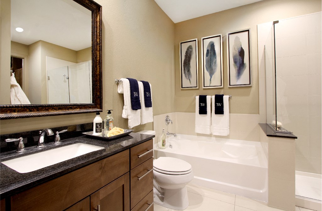Spacious bathroom with oval soaking tub, separate shower with glass enclosure, and granite slab vanity top Tuscany Walk Apartments in Houston.