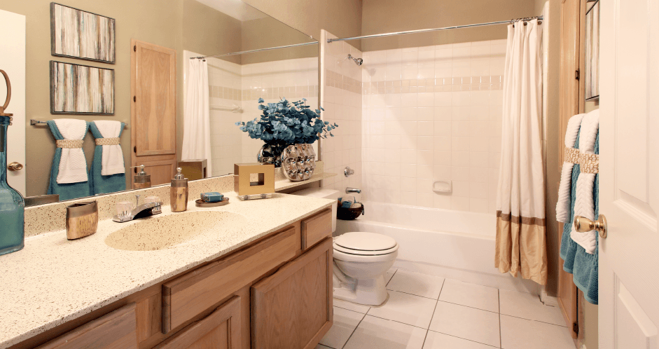 Luxury apartments with spacious bathrooms with tiled floors, extra storage and cabinet space, oval soaking tubs, granite countertops, and washed oak cabinets in north Dallas at Kensington Square Apartments.