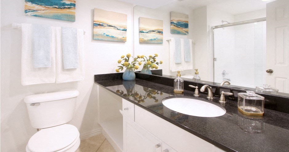 Luxury bathroom with oval soaking tub with glass enclosure, granite vanity top, and glass shower at Tuscany Villas Townhomes in Houston.