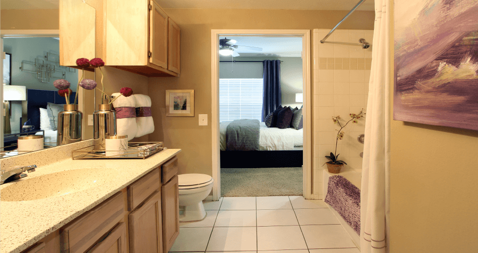 Luxury apartments with spacious bathrooms with tiled floors, extra storage and cabinet space, oval soaking tubs, granite countertops, and washed oak cabinets in north Dallas at Kensington Square Apartments.