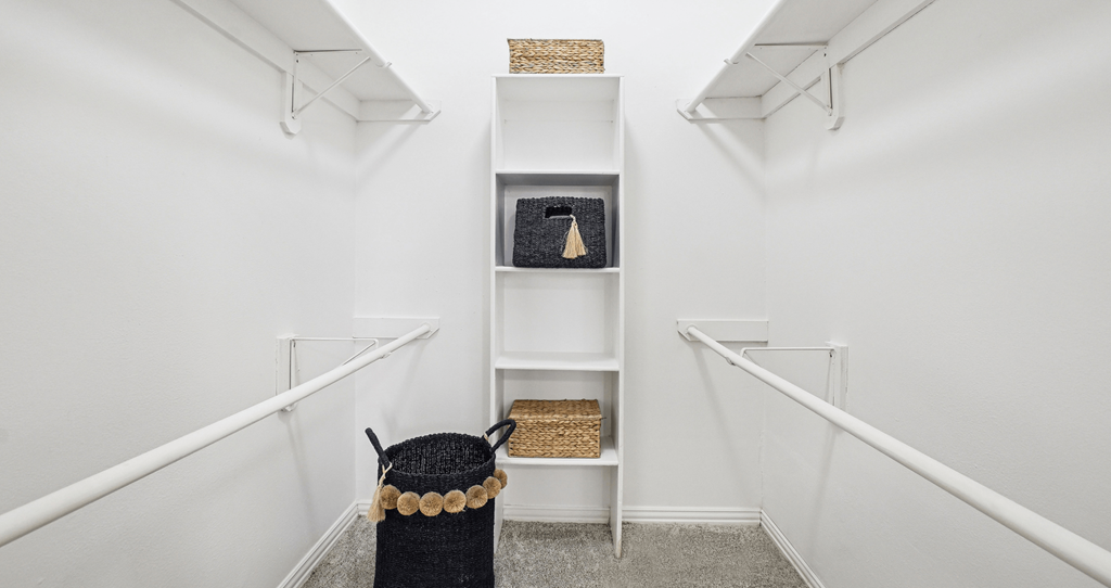 A hallway with white walls and a black trash can.