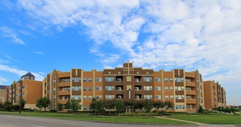 A large apartment building with a green lawn in front.