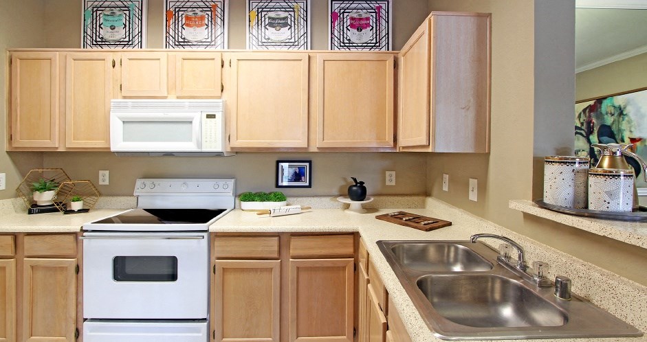 Luxury apartments with spacious kitchen, wood plank floors, breakfast bar, washed oak cabinets, granite countertops, extra pantry storage, and 9-foot ceilings at Kensington Square Apartments.