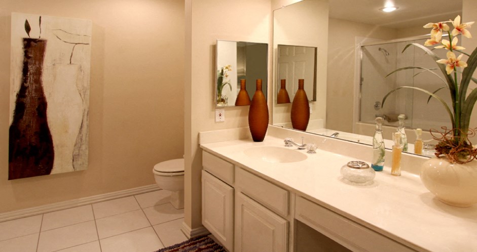 Luxury apartments with spacious bathrooms with tiled floors, extra storage and cabinet space, oval soaking tubs, built-in vanity, glass shower and white cabinets in at The Dorchester Apartments in north Dallas.