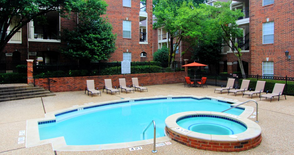 Gated community near the Galleria with brick exteriors, lush landscaping, two swimming pools with poolside lounge chairs, spa, and sauna at The Dorchester Apartments in north Dallas.