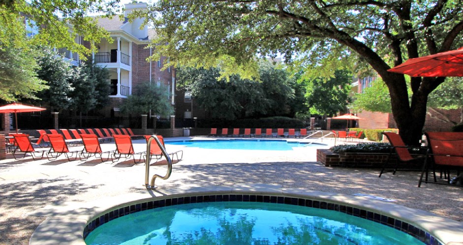 Gated community near the Galleria with brick exteriors, lush landscaping, two swimming pools with poolside lounge chairs, spa, and sauna at The Dorchester Apartments in north Dallas.