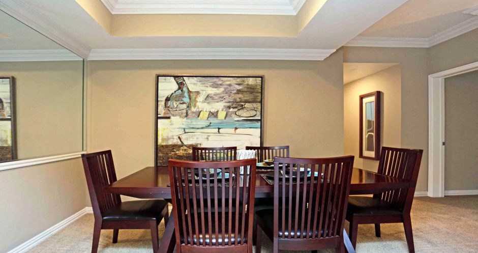 Spacious dining room area with mirror accent wall and kitchen with breakfast bar at Tuscany Lane Apartments in Houston.