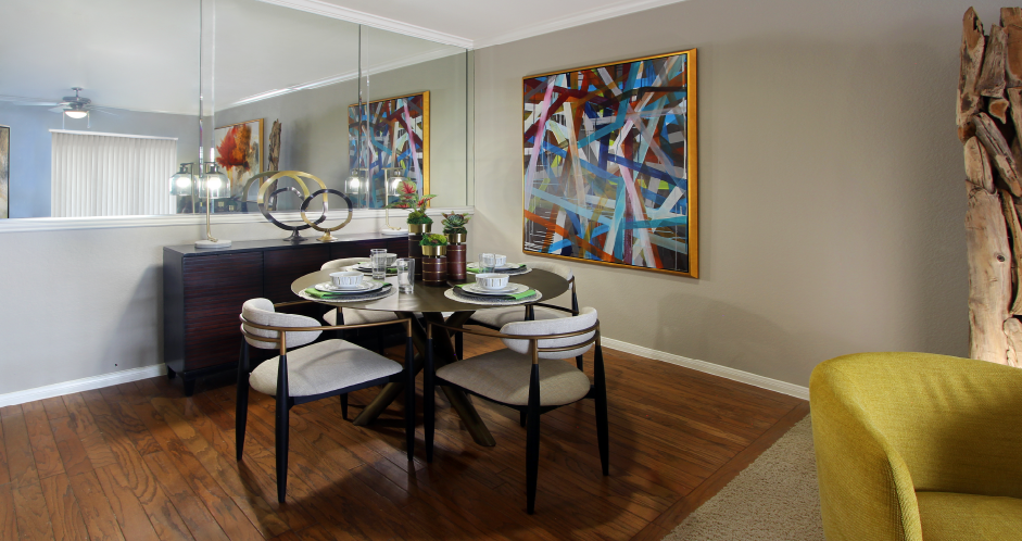 Luxury apartments with spacious dining room, wood plank floors, breakfast bar, mirror accent wall, and 9-foot ceilings at Kensington Square Apartments.