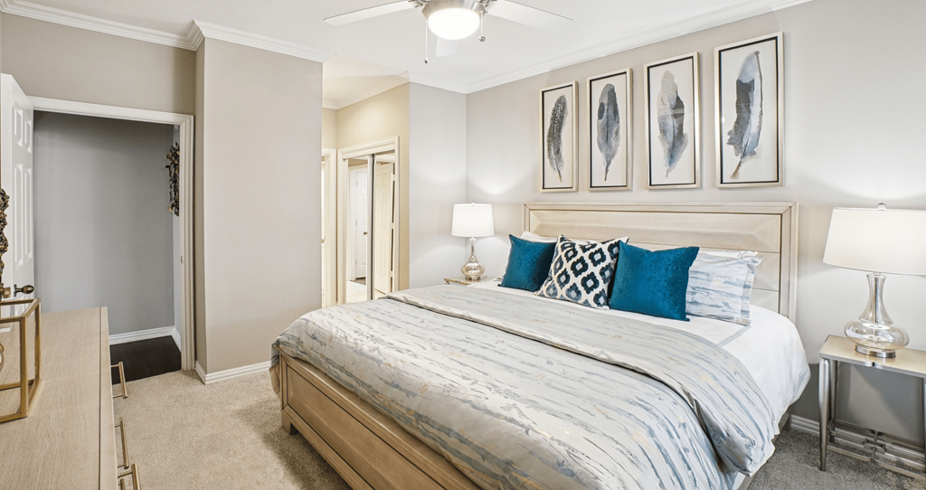 A bedroom with a bed, nightstands, and pictures on the wall.