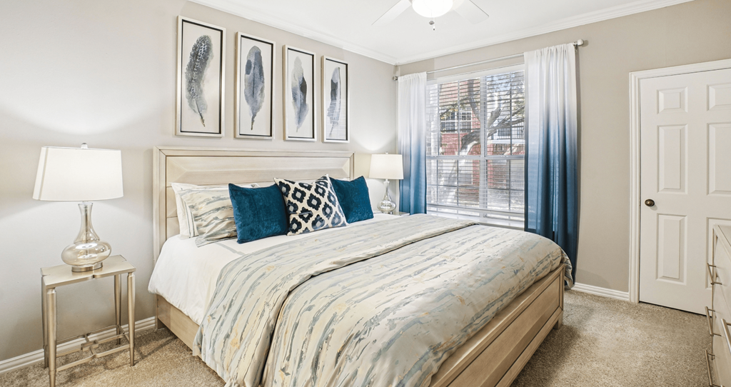 A bedroom with a bed, two lamps, and pictures on the wall.