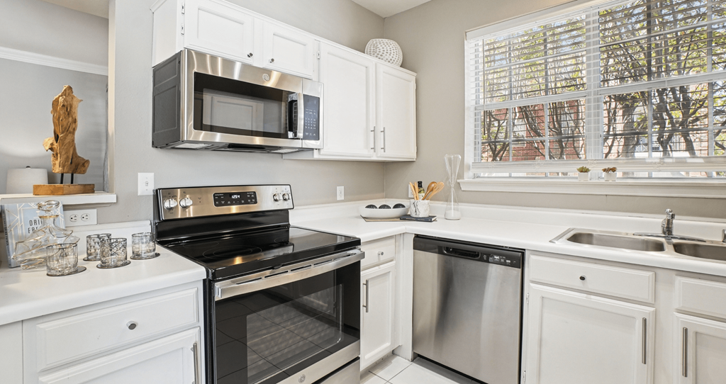 A modern kitchen with white cabinets and stainless steel appliances.