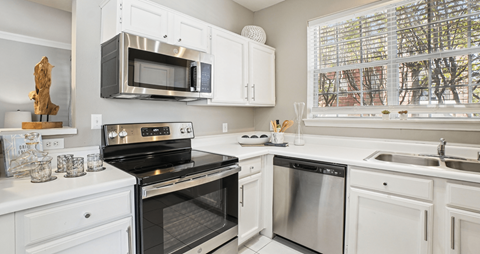 A modern kitchen with white cabinets and stainless steel appliances.