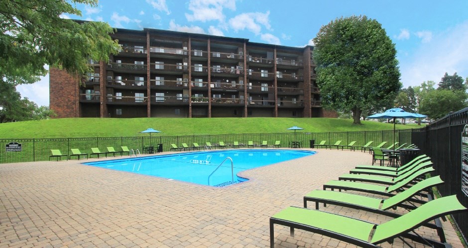 Resort-style saltwater pool with huge sun deck, poolside lounge chairs, and park-like setting with lots of trees and scenic views at Embassy Park Apartments in Omaha, Nebraska