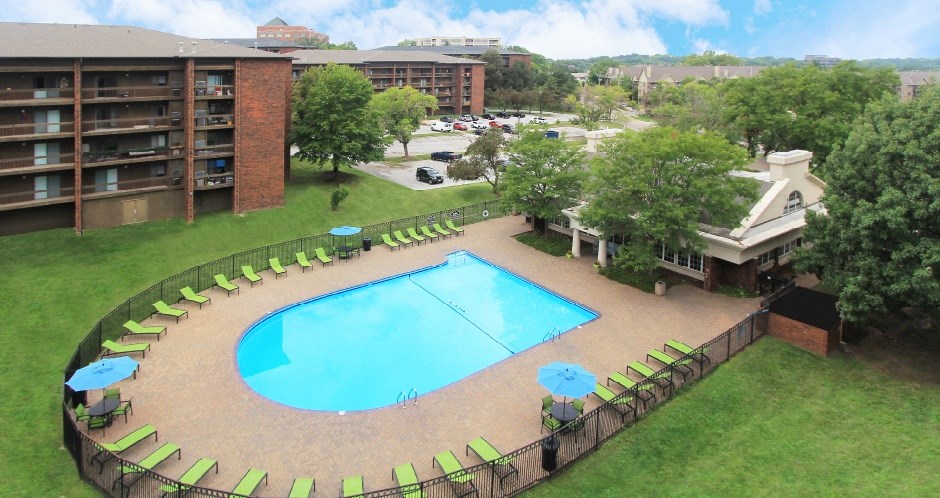 Resort-style saltwater pool with huge sun deck, poolside lounge chairs, and park-like setting with lots of trees and scenic views at Embassy Park Apartments in Omaha, Nebraska