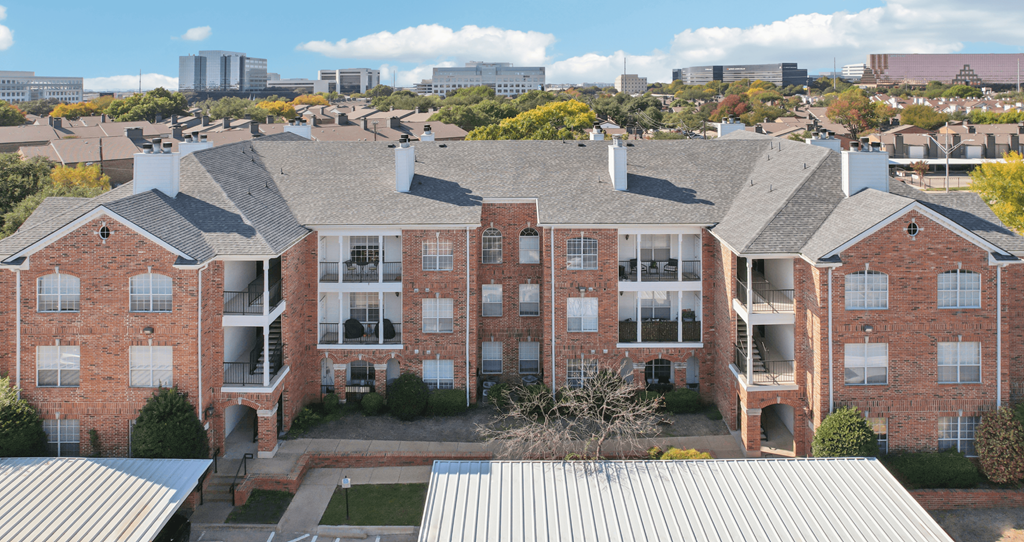 A large red brick building with a metal roof and a courtyard in the center.
