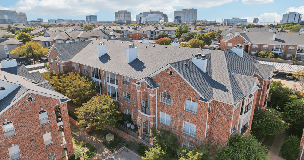 A large red brick building with a grey roof and a tree in front of it.